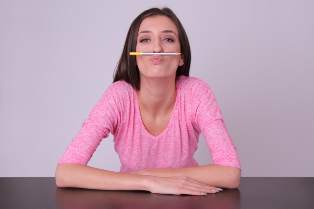 鼻と唇でペンを挟む女性